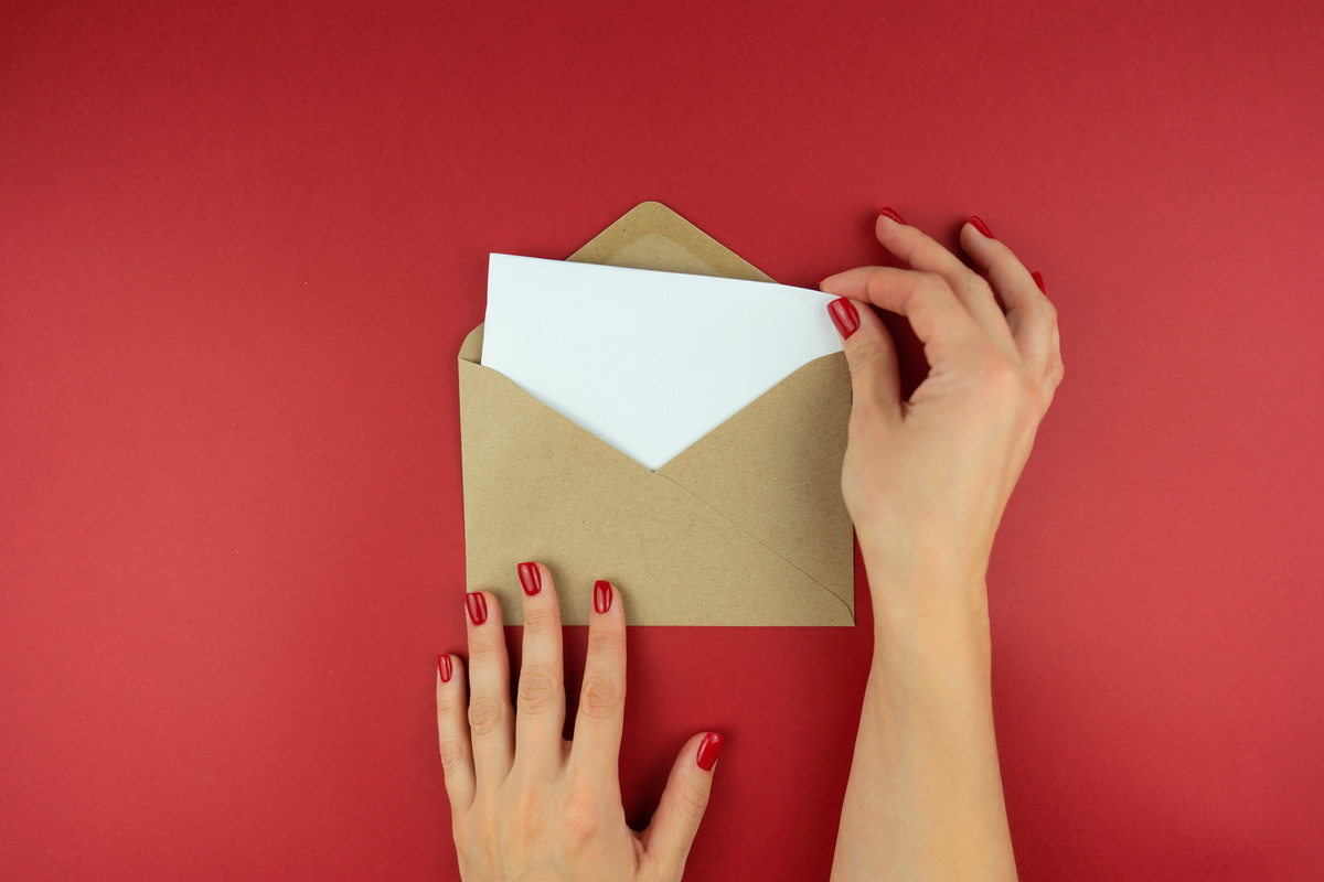 A woman holds a letter in an envelope in her hands
